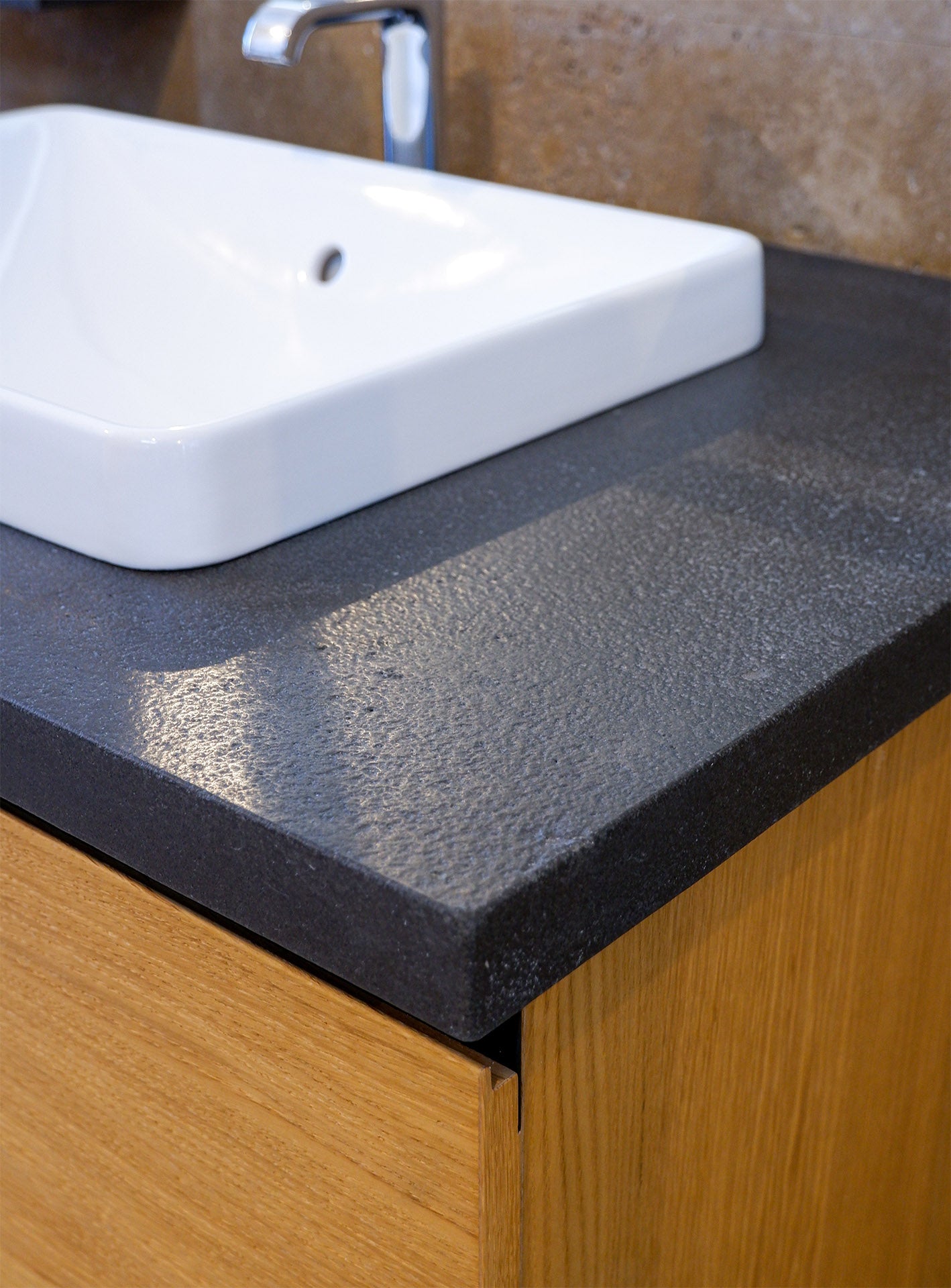 dettaglio del piano top in pietra naturale nera e lavabo a incasso in ceramica bianca di stone art