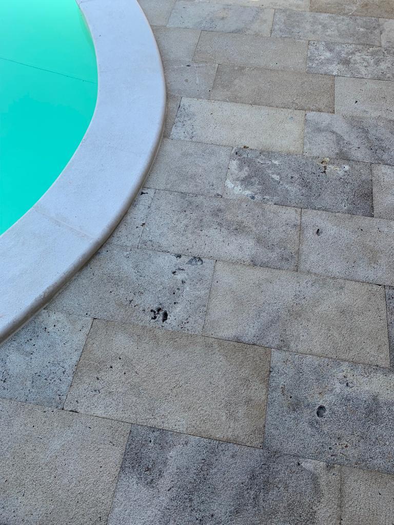 piastrelle con superficie ruvida granigliata ideali per un bordo piscina in travertino country